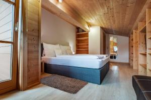 ein Schlafzimmer mit einem Bett in einem Zimmer mit Holzdecken in der Unterkunft Active Chalet in Maria Alm am Steinernen Meer