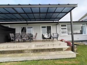 a patio with chairs and a table under awning at Home with a view in Otorohanga