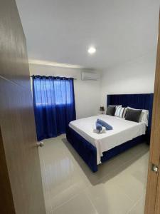 1 dormitorio con cama y cortina azul en Mountain View Cibao, en Santiago de los Caballeros