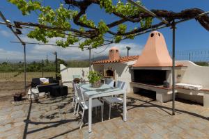 d'une terrasse avec une table et un four à pizza. dans l'établissement 1 - Villa Is Orrosas - Apartments 1 - Sa Crai Apartments Sardinian Experience, à Lotzorai