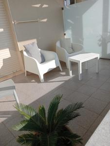 a lobby with white chairs and tables and a plant at La Scogliera in Avola