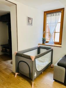 ein Babybett in einem Zimmer mit Fenster in der Unterkunft LA RUELLE ALSACIENNE, Charme Alsacien et Confort Moderne in Riquewihr