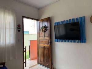 a flat screen tv hanging on a wall at Chalé beira mar Jacaraipe in Serra