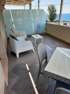 a patio with white chairs and tables and the ocean at La Scogliera in Avola
