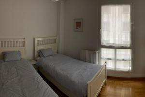 two beds in a bedroom with a window at La Catedral Home in Burgos