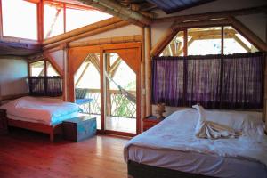 1 dormitorio con 2 camas en una habitación con ventanas en Bambu Guest House, en Tzununá
