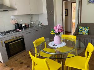 a dining room table with yellow chairs and a vase of flowers at La casa di Nana’ in Pisa