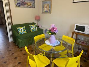 a living room with a glass table and yellow chairs at La casa di Nana’ in Pisa +16 photos