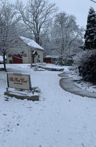 un patio cubierto de nieve con un cartel frente a una casa en The Red Coat en Niagara on the Lake