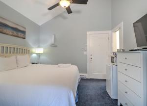 a bedroom with a white bed and a flat screen tv at The Inn at Sea Chambers in Ogunquit