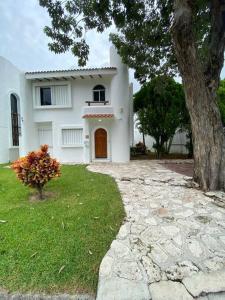 Una casa blanca con un árbol delante. en Villa Vaoli, en Playa del Carmen