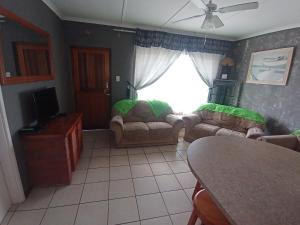 a living room with two couches and a window at Neptune corner in Hibberdene