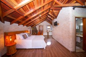 a bedroom with a white bed and a brick wall at Pousada Alpes da Mantiqueira in Monte Verde