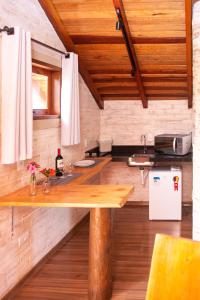 eine Küche mit einem Holztisch und einem Kühlschrank in der Unterkunft Pousada Alpes da Mantiqueira in Monte Verde