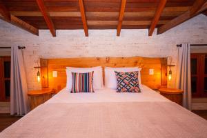 um quarto com uma grande cama branca e 2 almofadas em Pousada Alpes da Mantiqueira em Monte Verde