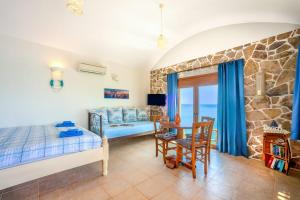 a bedroom with a bed and a desk and a table at Plaka Beach Cottages in Pláka