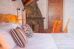 Schlafzimmer mit einem Bett und einem Steinkamin in der Unterkunft Pousada Alpes da Mantiqueira in Monte Verde