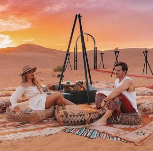 a man and a woman sitting on large tires in the desert at Merzouga Nice luxury Camp in Merzouga +81 photos