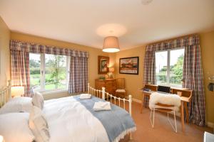 a bedroom with a bed and a desk and two windows at Cedar Lodge in Portpatrick