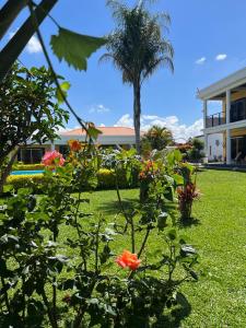 a garden with flowers and a palm tree and a building at COCODY ROC in Ambohidratrimo