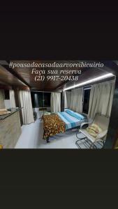 マンガラチバにあるPousada Casa na Árvoreのヒョウのベッドと椅子が備わる客室です。