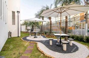 a patio with picnic tables and an umbrella at SanLoft Expo Inn Tietê 03 Top 1 in Sao Paulo