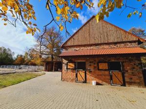 ein Backsteingebäude mit einem roten Dach mit zwei Türen in der Unterkunft Ranczo Popowice in Pątnów