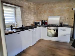 a kitchen with white cabinets and a stove top oven at Gite du four à pain in Benais