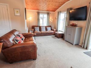 a living room with leather furniture and a flat screen tv at Brightwater Lodge in Windermere