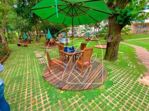 stół i krzesła pod zielonym parasolem w parku w obiekcie Thermas Paradise - Duplex w mieście Rio Quente