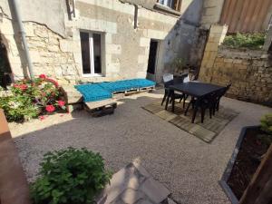 un patio con una mesa y un banco con un cojín azul en Gite du four à pain, en Benais