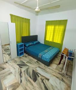 a bedroom with a bed and a table and yellow curtains at Simple Beseri Homestay in Kangar