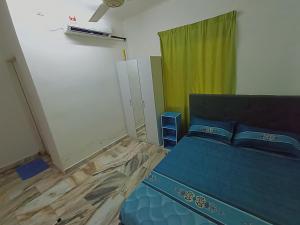a bedroom with a blue bed and a green curtain at Simple Beseri Homestay in Kangar