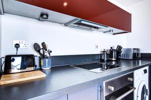 a kitchen with a counter with a sink and a stove at Stylish 2 Bedroom Apartment on the Waterfront in Ipswich