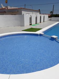 a large blue swimming pool next to a white building at Tramontana Villa in Cala'n Porter