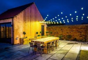 una mesa de madera y sillas en un patio por la noche en The Birches, Ashlin Farm Barns en Lincoln