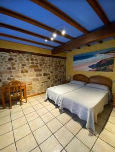1 dormitorio con cama y pared de piedra en Posada La Capía, en Vargas