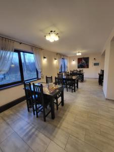 Un comedor con mesas y sillas y ventanas. en Pensiunea Castel, en Timisul de Jos