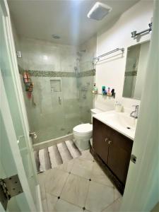 a bathroom with a shower and a toilet and a sink at Bay Beach Bungalow in San Diego