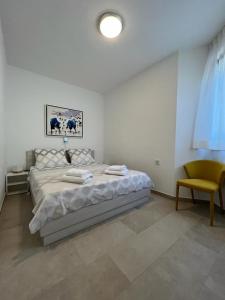 a white bedroom with a bed and a chair at APARTMENTS HOUSE BARBARA 2 in Kornić +67 photos