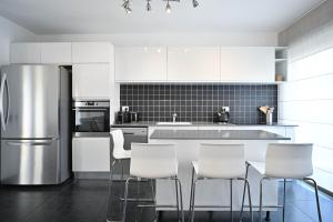a kitchen with a stainless steel refrigerator and white cabinets at Escapade by HolyGuest in Tel Aviv
