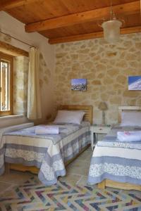 um quarto com 2 camas e uma parede de pedra em Villa Ariadne em Melidhónion
