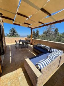 un patio al aire libre con sofás, mesa y sillas en Villa Ariadne, en Melidhónion