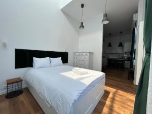 a bedroom with a large white bed and a kitchen at Loft Premium Apartments in Łódź