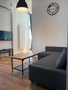 a living room with a couch and a clock on the wall at Loft Premium Apartments in Łódź