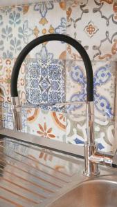 a kitchen sink with a faucet and a tile wall at 61cavour in Santena