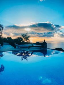 a swimming pool with a sunset in the background at Casa Vista Pájaro in Puntallana