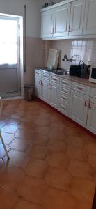 a kitchen with white cabinets and a tile floor at Apartamento Abril in Gouveia