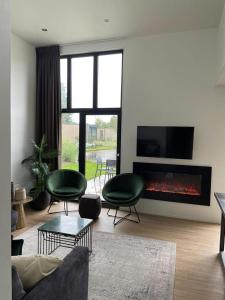a living room with a couch and chairs and a fireplace at Velduil 52 in Hulshorst