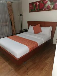 1 cama con sábanas blancas y almohada naranja en Hotel Splendor by Friends Company, en Bogotá